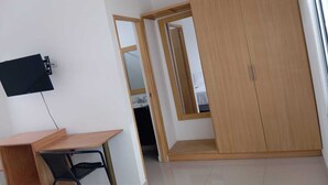 A room with a desk, chair, wardrobe, and a TV mounted on the wall. - Hotel Casa Grande  (Agustín Codazzi)