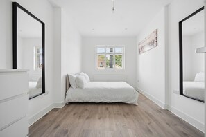 Un dormitorio con cama, ventana y espejo.