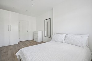 Ein Schlafzimmer mit einem Bett, einem Kleiderschrank, einer Kommode und einem Spiegel.