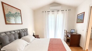 A bedroom with a bed, a desk with a laptop, a window with curtains, and two wall-mounted paintings. - Villa Fiammetta, 500 meters from the beach (Castiadas)