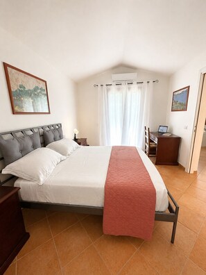 A bedroom with a bed, a desk with a laptop, a window with curtains, and two wall-mounted paintings. - Villa Fiammetta, 500 meters from the beach (Castiadas)