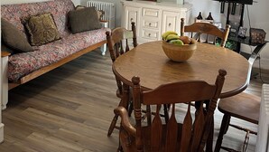 Ein Essbereich mit einem Holztisch, Stühlen, einem Deckenventilator, einer Uhr und einem Fernseher.