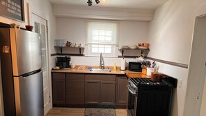 Eine kleine Küche mit Kühlschrank, Herd, Mikrowelle und Holzschränken.