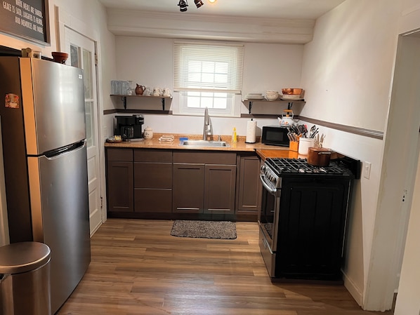 Cocina compacta con refrigerador, estufa, microondas y gabinetes de madera.