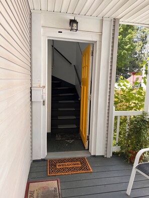 Una escala que condueix a una porta amb un estriau de benvinguda.