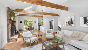 A spacious living area with a fireplace, wooden beams, a dining area, and a kitchen with modern appliances.