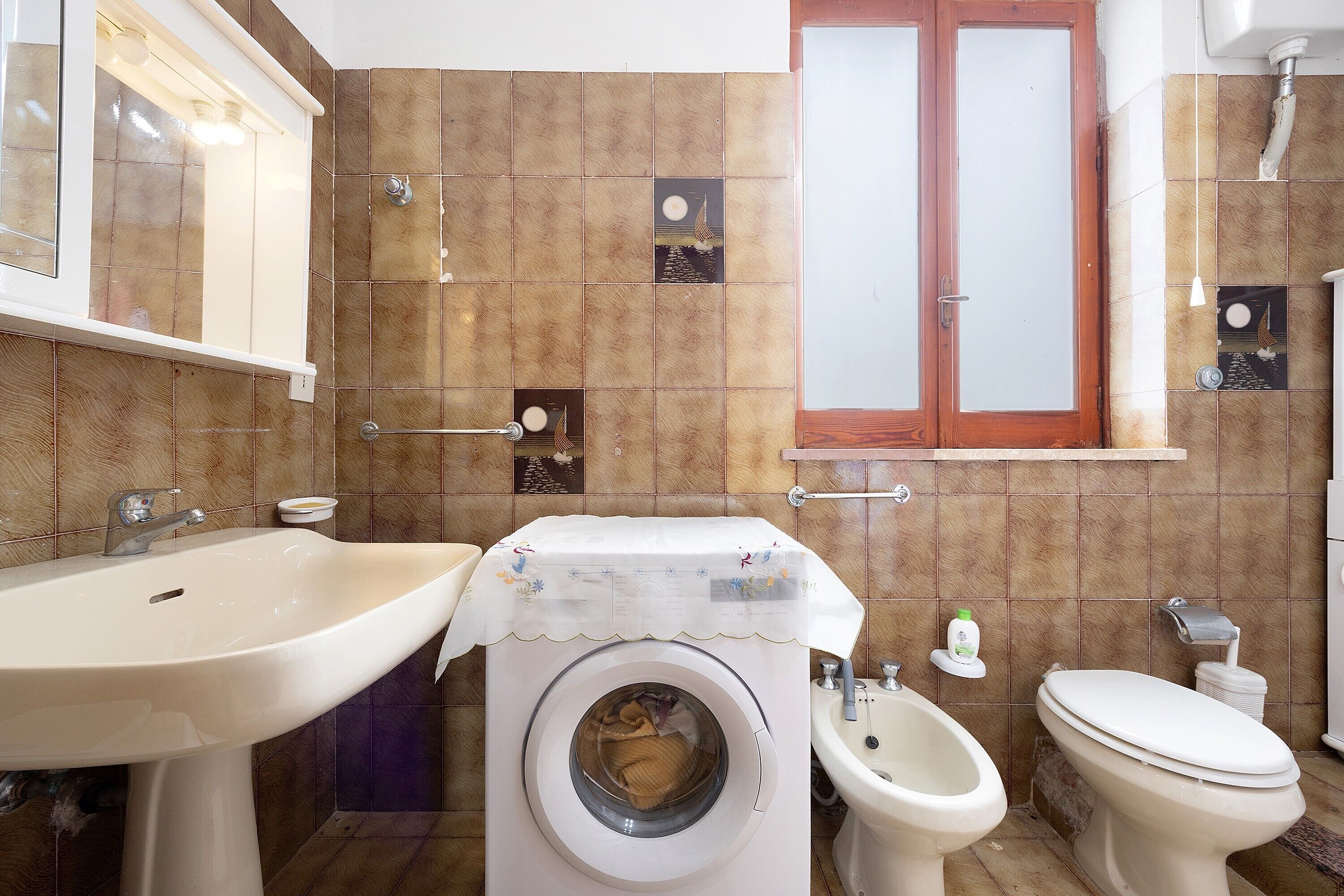 Un bagno con lavandino, bidet, WC e lavatrice.