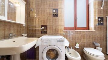 Un bagno con lavandino, bidet, WC e lavatrice.