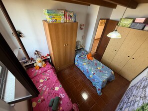 Ein Schlafzimmer mit einem Holzschrank, einem Bett mit rosa und blauer Bettdecke und einem kleinen Tisch mit Spielzeug.