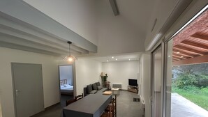 Interior moderno com área de refeições, sofá, TV e vista para o verde.