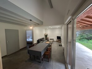 Moderni sisustus, jossa on ruokailutila, sohva, televisio ja näkymä vehreään maisemaan.