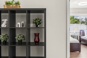 A modern room with a black shelving unit containing decorative items, a red vase, and potted plants. - Private 3BD2BA Dream Pool Escape Close To Parks (Davenport)