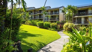 A hotel with multiple balconies, lush greenery, and a well-maintained lawn. - Kona Makai 3-102 No Stairs, Ocean View, With AC! (Kailua-Kona)