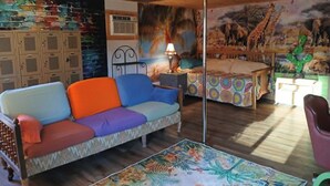 Une pièce comprenant un canapé, une table, une lampe et une fresque murale.