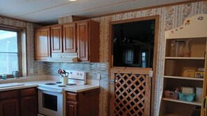 Une cuisine avec des meubles de rangement en bois, une cuisinière et un réfrigérateur.