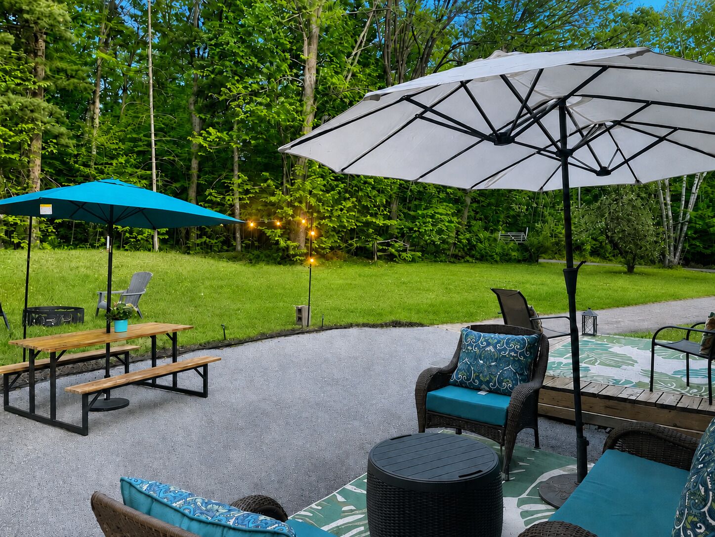 Un espace extérieur aménagé en terrasse, avec une table et des chaises, une table ronde et deux parasols.
