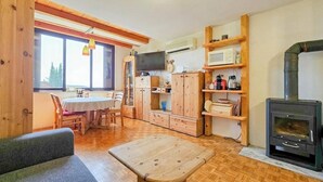 Ein gemütliches Blockhauszimmer mit einem Holzespeisetisch, Stühlen, einem Fernseher, einem Kamin und integrierten Regalen.