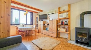 Ein gemütliches Blockhauszimmer mit einem Holzespeisetisch, Stühlen, einem Fernseher, einem Kamin und integrierten Regalen.