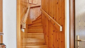 Eine Holztreppe mit Handlauf, die zu einer Tür mit einem Metallgriff führt.