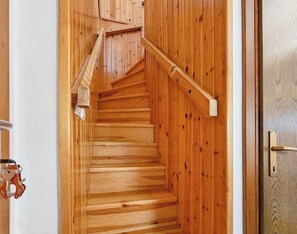 Eine Holztreppe mit Handlauf, die zu einer Tür mit einem Metallgriff führt.