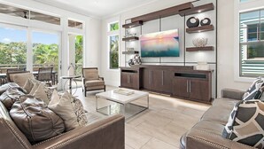 Een moderne woonkamer met een grote televisie, een eethoek en een keuken met donkerhouten kasten.