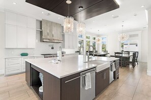 A modern kitchen with a large island, white cabinetry, stainless steel appliances, and pendant lighting. - ☀️ The Sandbar Social | Resort Pool w/ Swim-Up Bar | 3-Min to Beach (Destin)
