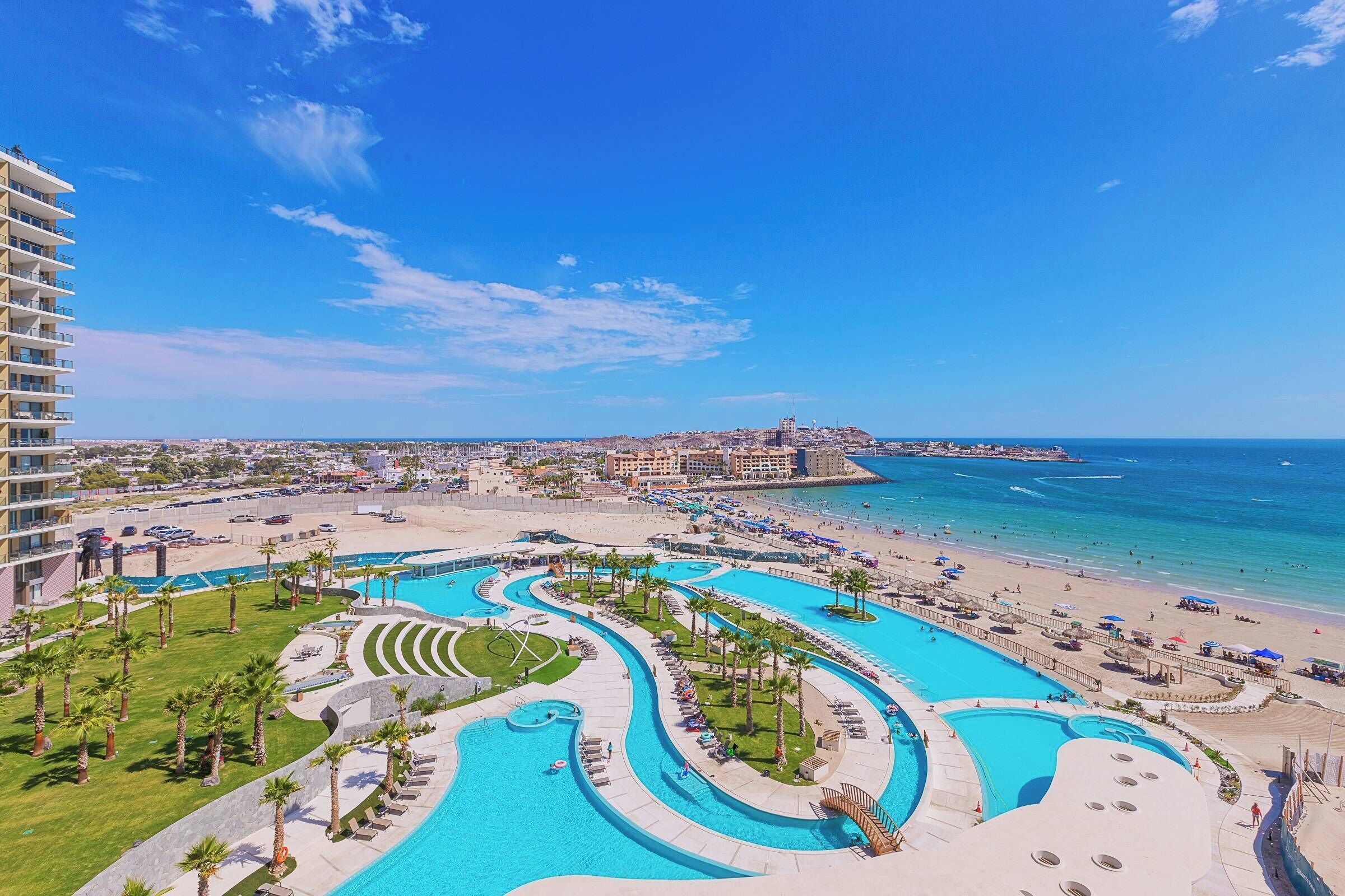 Et resort med flere swimmingpools, en strand og udsigt over havet.