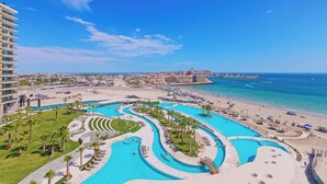 Een resort met meerdere zwembaden, een strand en uitzicht op de oceaan.