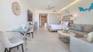 A modern hotel room with a glass dining table, a sofa, a bed, a ceiling fan, and a wall clock. - Brand New Sonoran Star Luxury Oceanfront Studio (Puerto Peñasco)