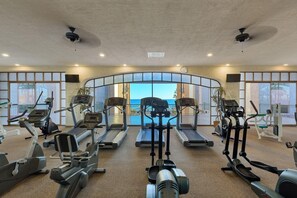 Ein Fitnessraum mit Laufbändern, Ergometer und Crosstrainern, die in Reihen angeordnet sind.