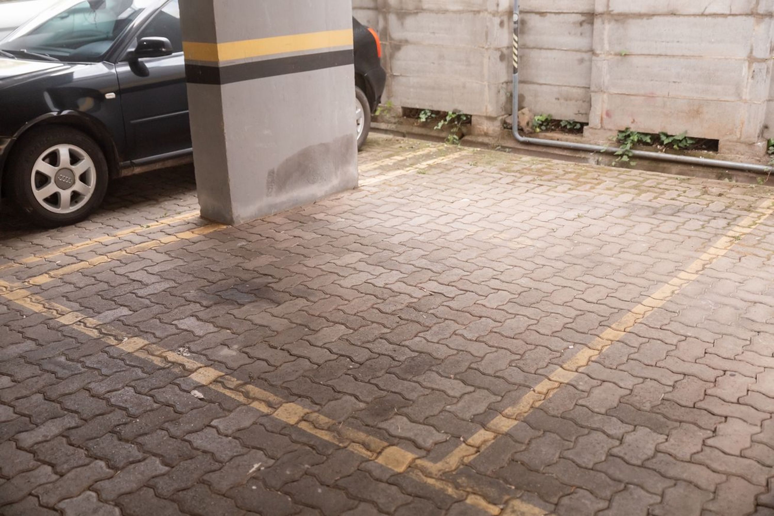 A paved parking area with a car and a pillar.