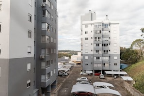 Edifício residencial com vários andares e área de estacionamento em frente.