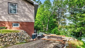 A house with a stone wall, a wooden deck, and a picnic table. - 2 bedroom walkout on Rice Lake/Mississippi River with dock for your boat! (Brainerd)