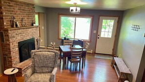 A living room with a fireplace, a dining area, and a bench. - 2 bedroom walkout on Rice Lake/Mississippi River with dock for your boat! (Brainerd)