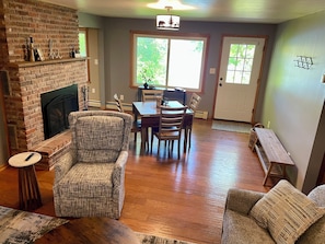 A living room with a fireplace, a dining area, and a bench.