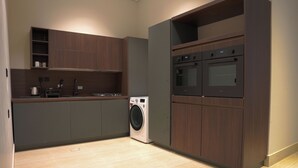 A modern kitchen with built-in appliances, grey cabinets, and a washing machine. - Orbitnet - MB25 (Madinah)