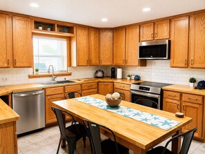 Una cocina moderna con armarios de madera, electrodomésticos de acero inoxidable y un comedor con mesa y sillas.