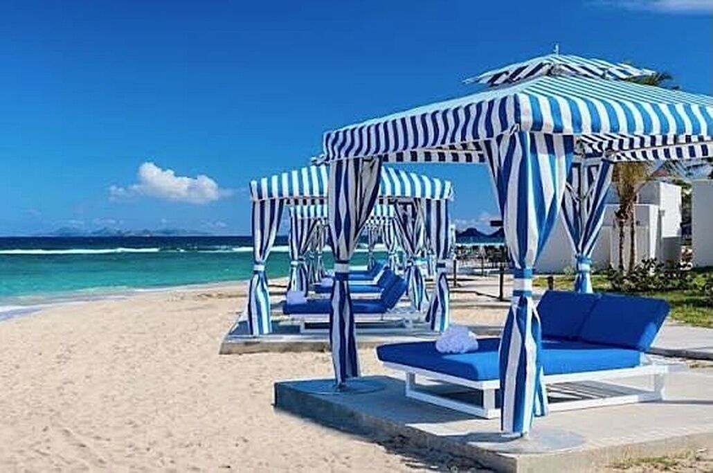 Ein Strand mit gestreiften Sonnenschirmen und Liegestühlen.