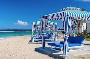 Ein Strand mit gestreiften Sonnenschirmen und Liegestühlen.