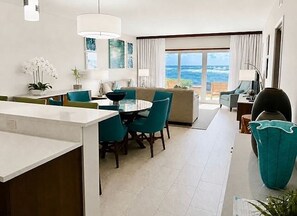 A modern hotel room with a dining area, a sofa, a TV, and a view of the ocean. - Spacious 3-bedroom condo in Dawn Beach at the JW Marriot. (Dawn Beach)