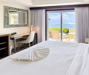 Ein Hotelzimmer mit Bett, Schreibtisch, Stuhl und Meerblick.