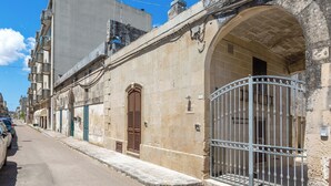 A street with a stone building featuring a large arched doorway and a metal gate. - L'Antica Corte - Camera Superior by BarbarHouse (Maglie)