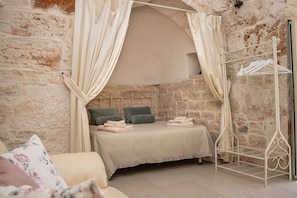 Ein Schlafzimmer mit Stehwänden, einem Bett, einem Wäscheständer aus Metall und einem weißen Baldachin.