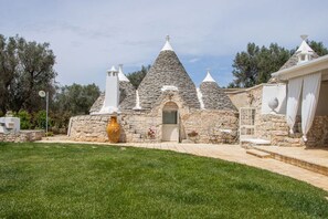 Un bâtiment en pierre avec des toits coniques, un grand vase et une petite table entourée de chaises, le tout en premier plan.