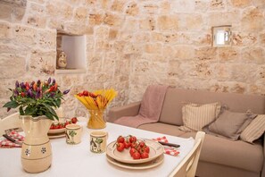 Eine Steinsäule, ein Tisch mit Tomatenscheiben, eine Vase mit Blumen und eine Schüssel Pasta.