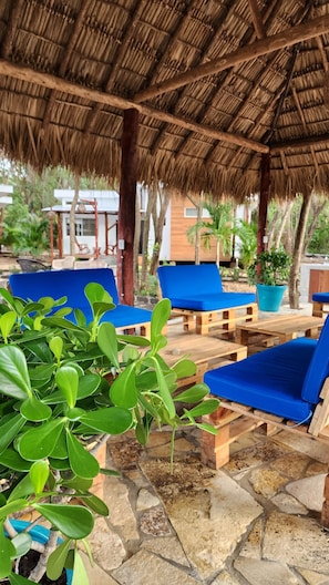 A covered outdoor seating area with blue lounge chairs and a thatched roof. - Ecovillas del Sur (San Juan del Sur)