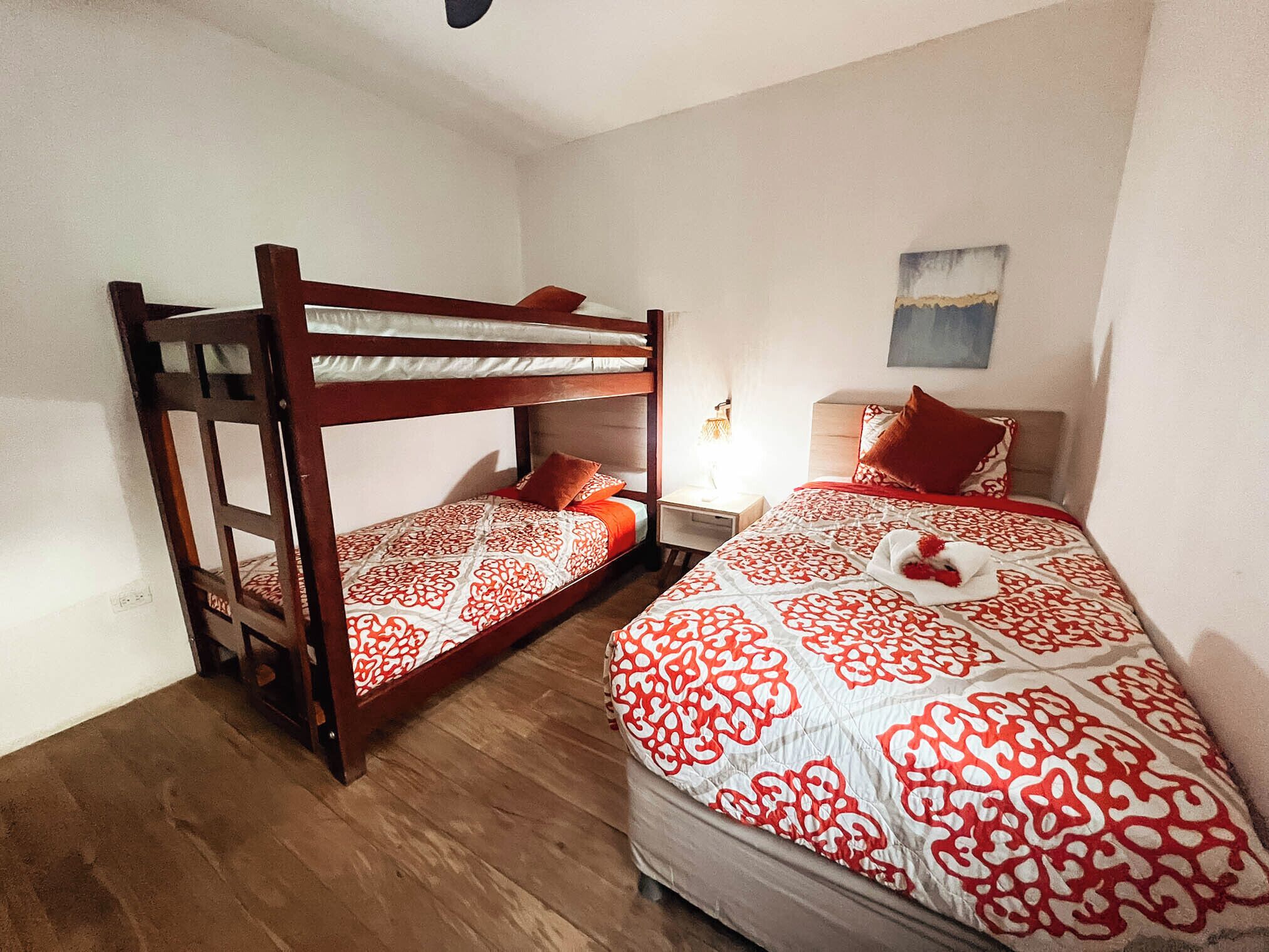 Ein Zimmer mit zwei Etagenbetten, einem Nachttisch mit Lampe und einem Wandbild.