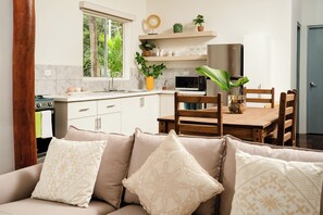 A modern kitchen with white cabinets, a microwave, and a wooden dining table with chairs.