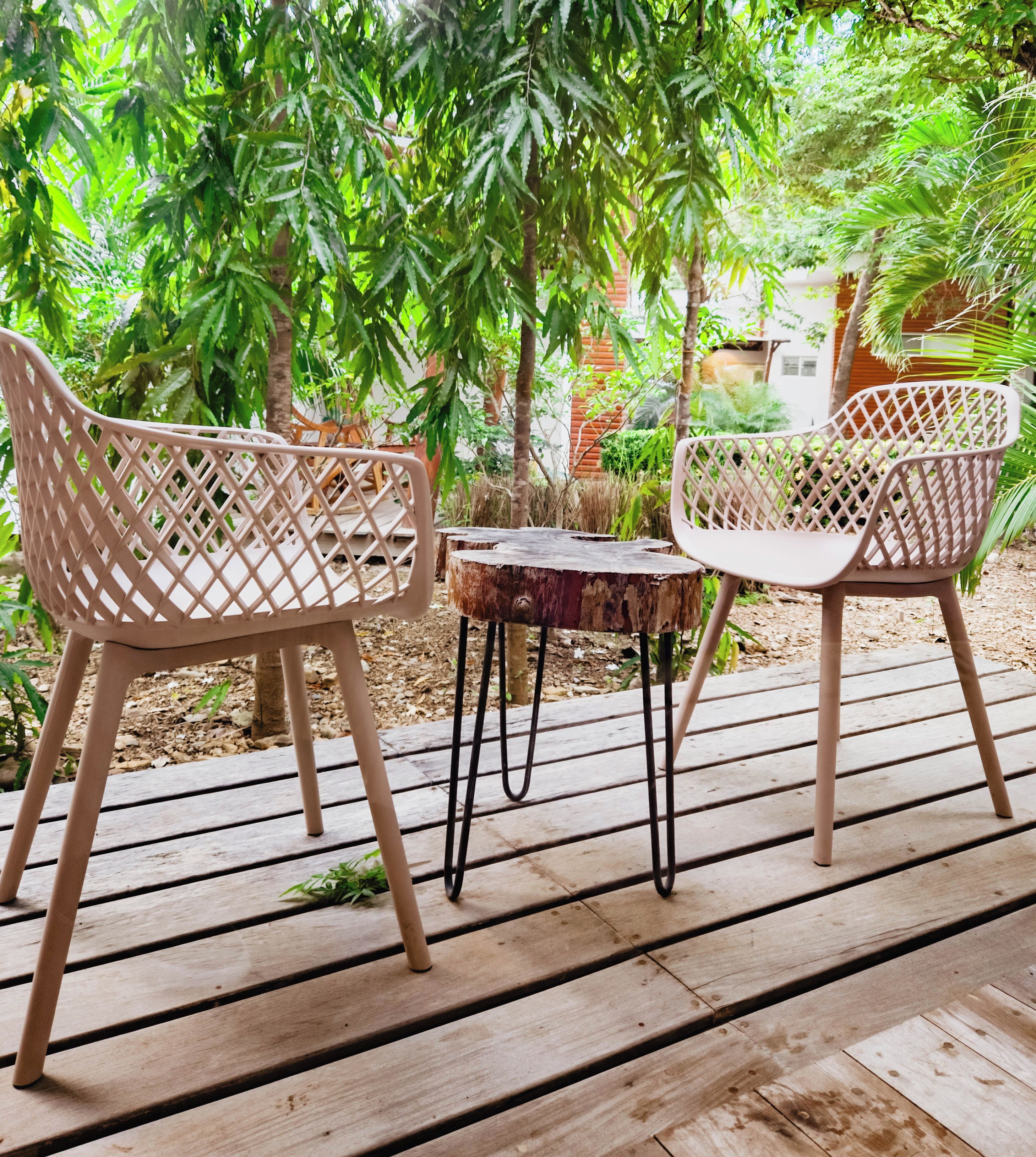 A wooden deck with two white chairs and a small table.