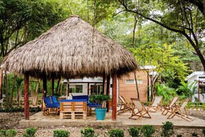 A thatched-roof hut with seating and a potted plant.
